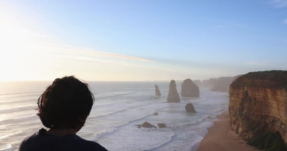 A person is looking out over the ocean on a foggy day