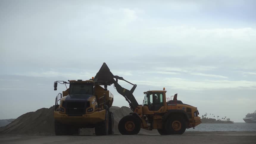 Bulldozers moving sand on beach