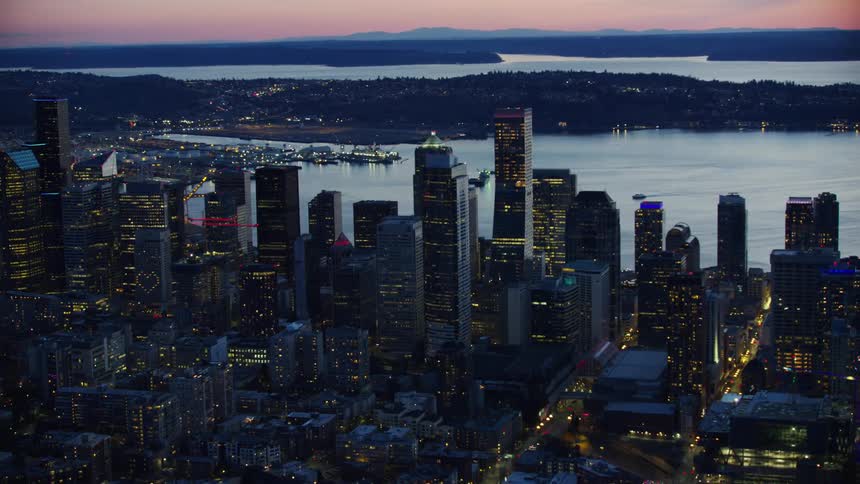 Awesome aerial of downtown Seattle under a clear pink sky after the sun has set and the sky glows orange and blue