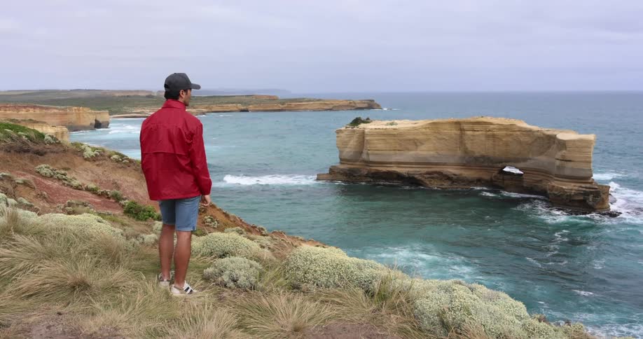 A man stands on an ocean cliff looking to the water