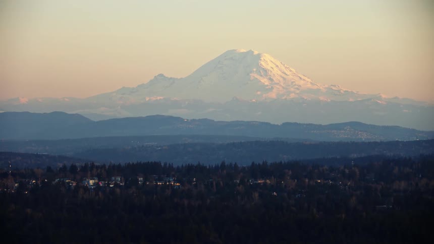 Mount Rainier rises beautifully in the background as the city of Seattle passes by in the foreground of this sunset aerial of the city landscape