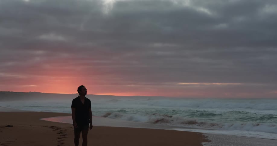 A man walking at the beach at sunset