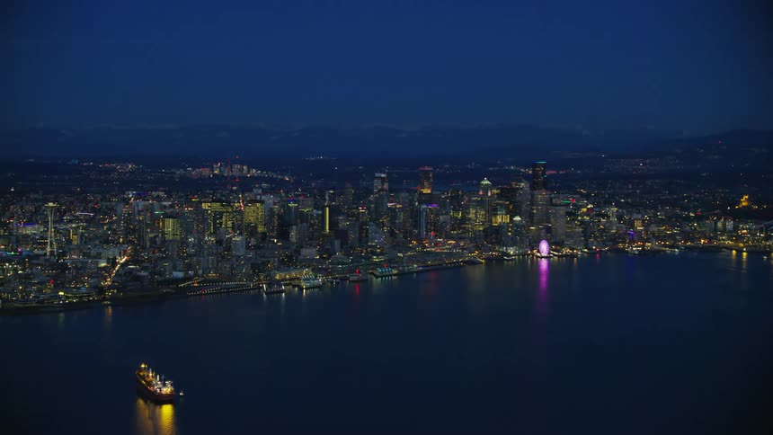 The city lights turn on in downtown Seattle as the camera slowly zooms out in this beautiful aerial after the sun has set