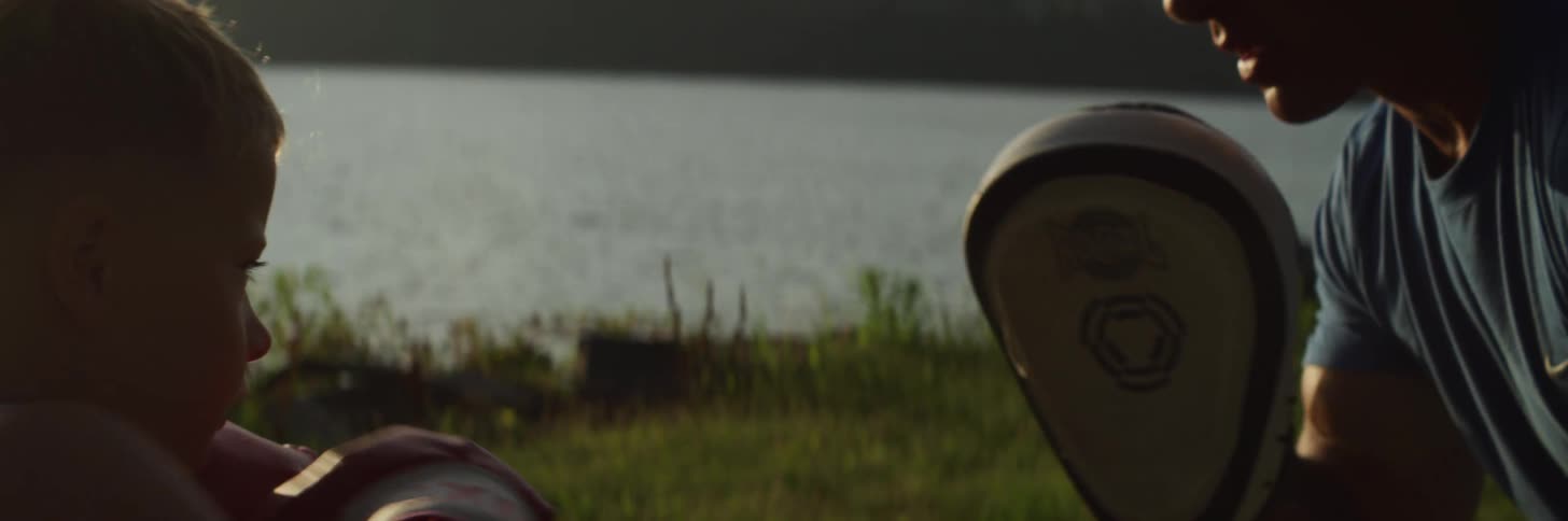 A man and a boy practicing boxing with grass and a lake in the background