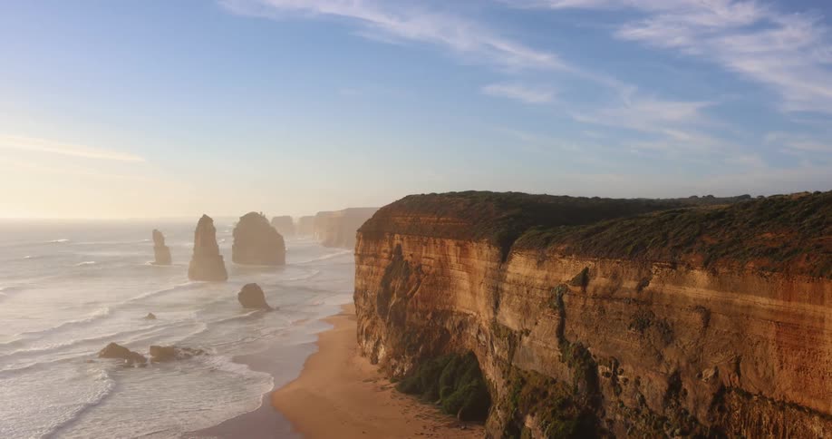 Waves rolling in to the shore with a large cliff