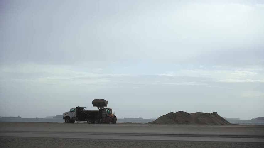 Dump truck and hauler working on beach