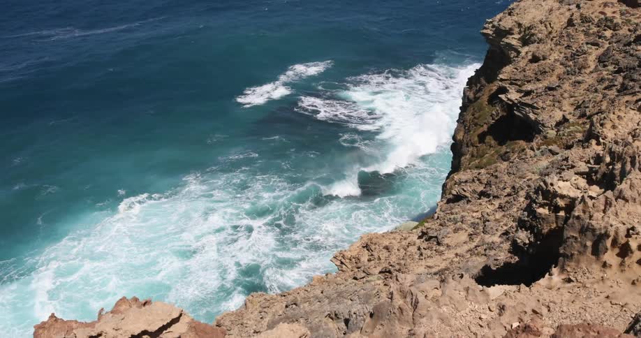 A view of water in the ocean hitting a cliffside