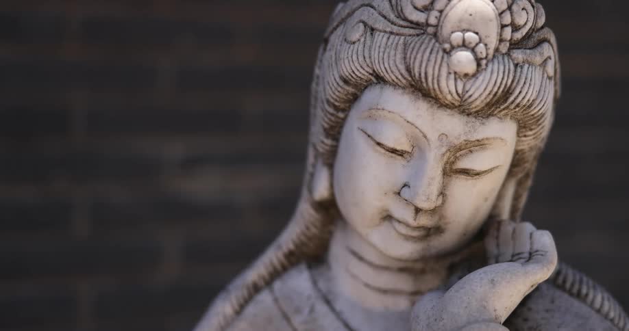 A statue with a brick wall in the background