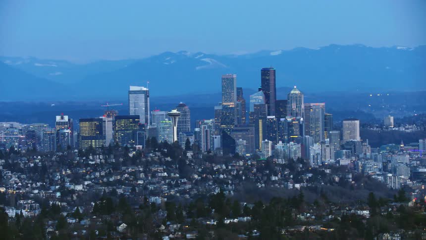 Downtown Seattle suburbs and skyscrapers pass by in this aerial of the city after the sun has set