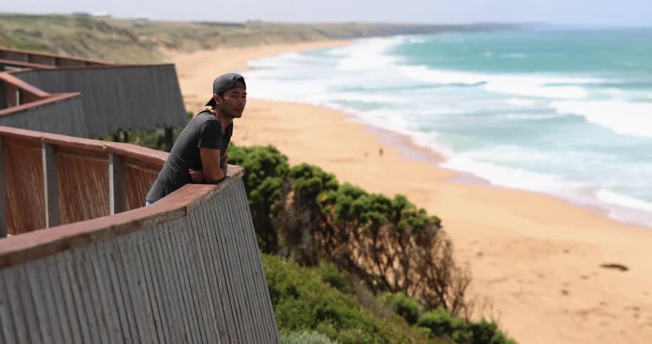 A man looking off a balcony at the sea