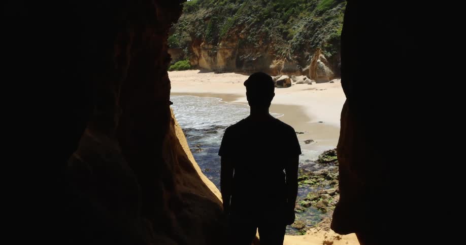 A man is standing in the cave by the water