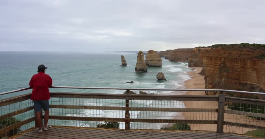 A man standing at a balcony overlooking the ocean