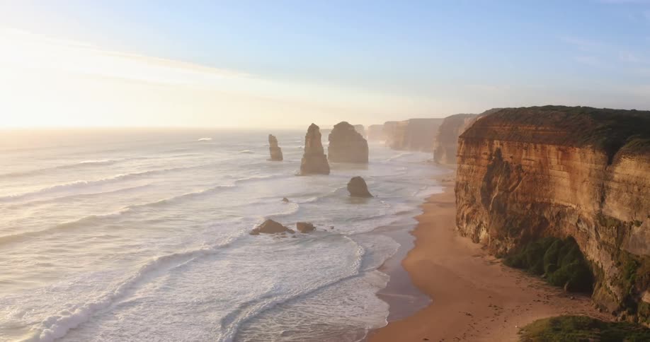 Rock promontories rising over the a beach coastline close to a cliff at sunset