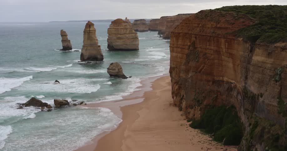 Ocean waves come to shore splashing around the twelve apostles rock formations