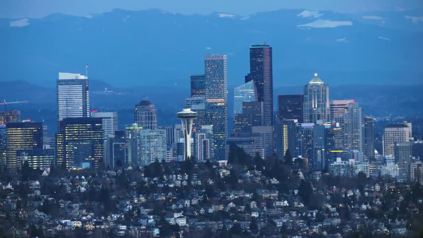 Slow zoom out reveal of downtown Seattle and the Lawton Park neighborhood with the Cascade Mountains in the background