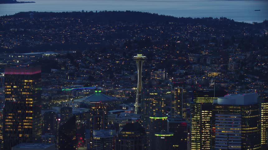 Slow zoom out reveal of the space needle and city skyscrapers passing by in the foreground showing the beauty and hills of Seattle