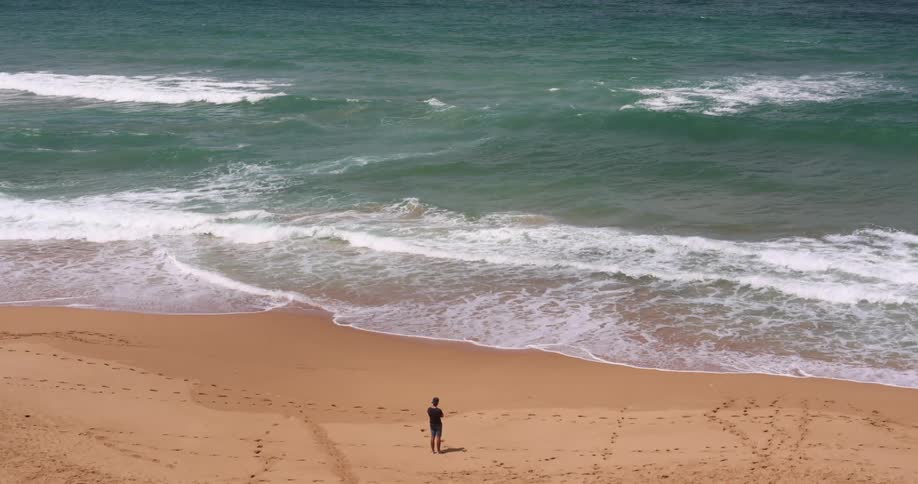 A person standing at the beach on a sunny day