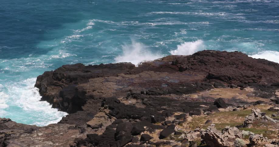 An aerial view of waves crashing in to rocks on the shore