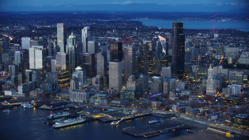Wide shot of Lake Washington, Downtown Seattle with the Puget Sound waterfront in the foreground as the skyscrapers reflect sunset light