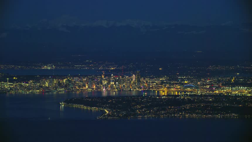 Downtown Seattle is lit brightly from this high altitude aerial in stunning blue hour light