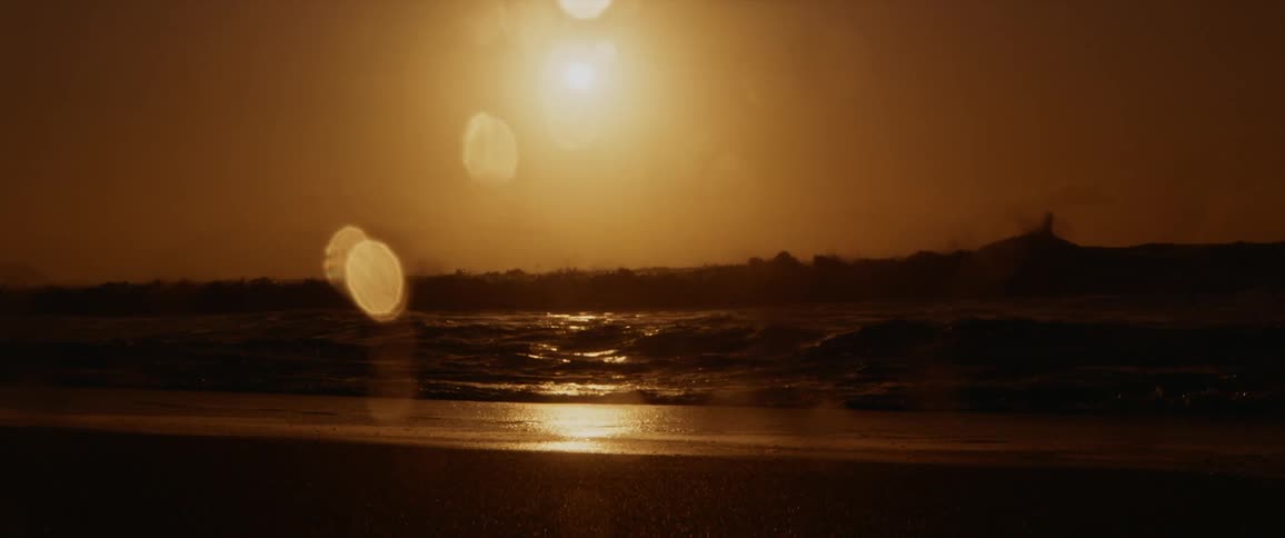 The beach glows golden yellow as waves break and splash