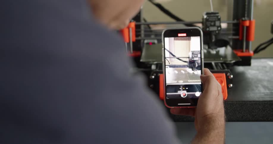 A person filming a working 3d printer with a smartphone