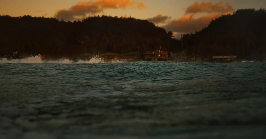 An ocean with waves with land houses the sky and clouds in the background