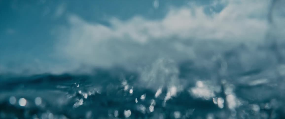 An ocean with waves of water with the sky and clouds in the background