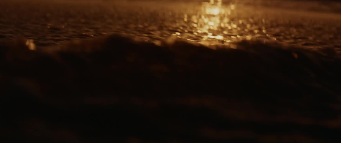 Golden sunset sunlight reflecting on the ocean waves washing over the beach sand