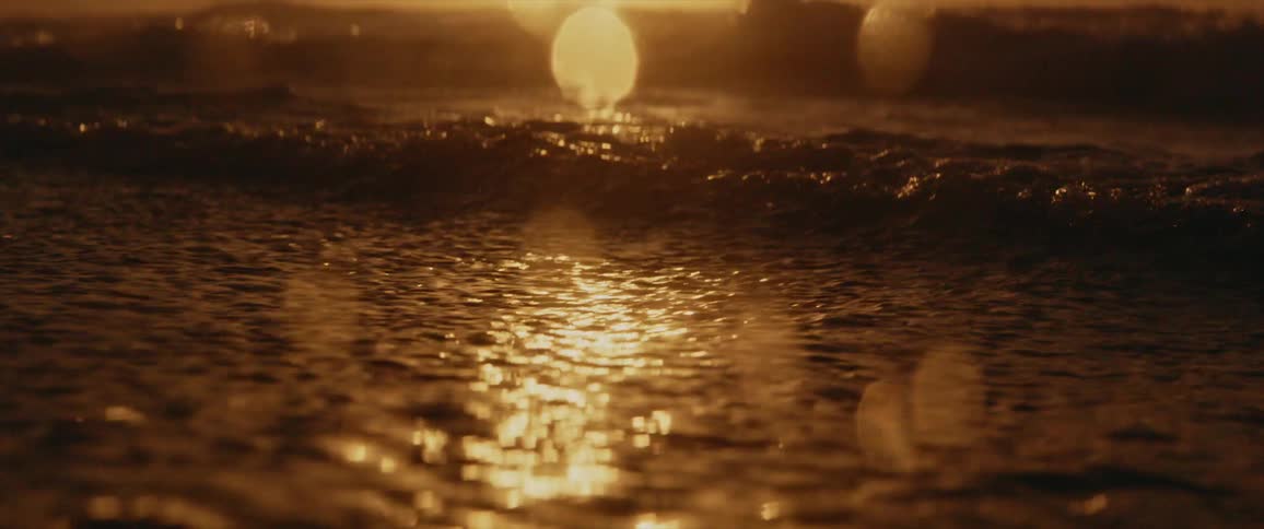 An ocean with waves of water with a sunset the sky and clouds in the background