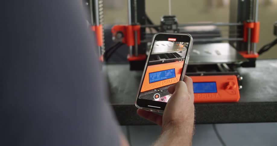 A person recording a 3d printer working in a factory