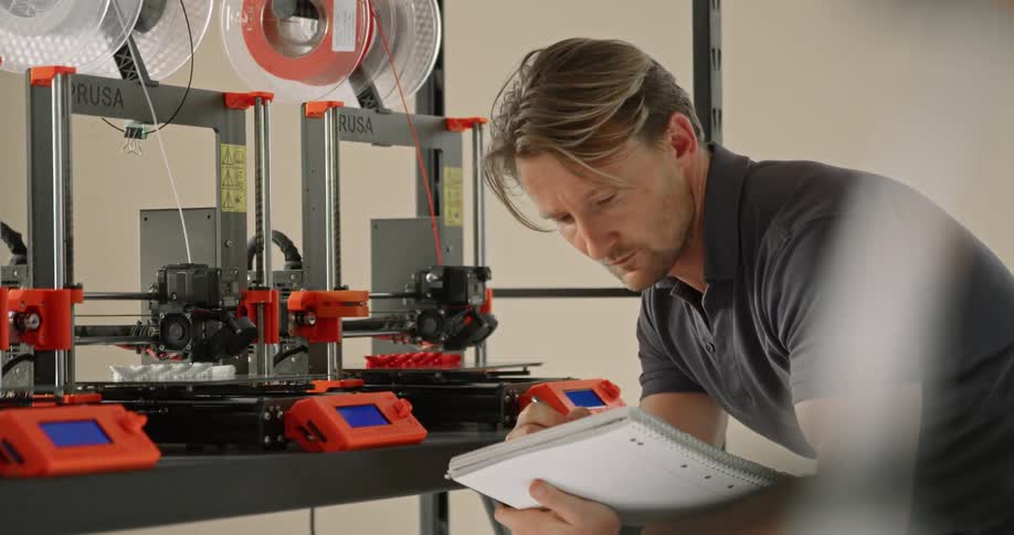A man takes notes as he watches 3d printers working