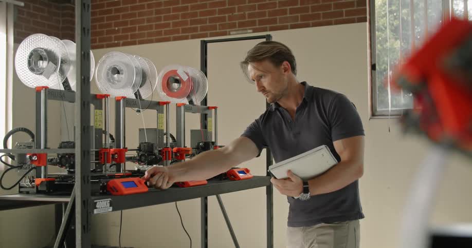A man in an office takes notes as he looks at machines