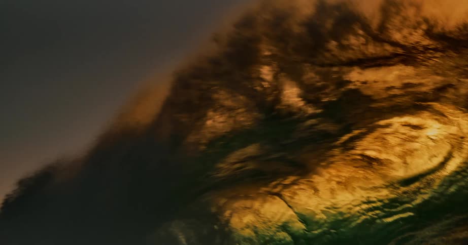 A large ocean waves rises high and crashes hard into the water