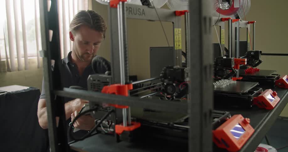 Man supervising working 3d printers on an office