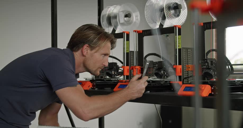 An employee watching 3d printers make products