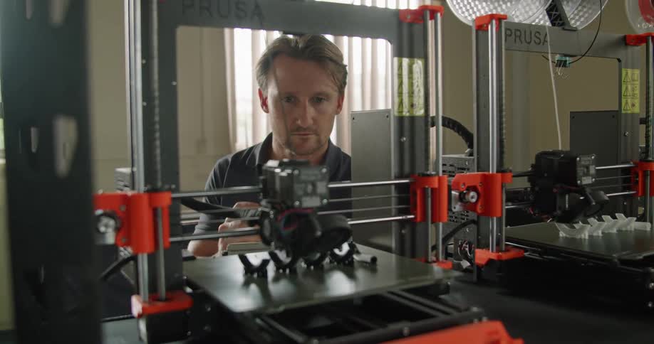 A man watching multiple 3d printers working