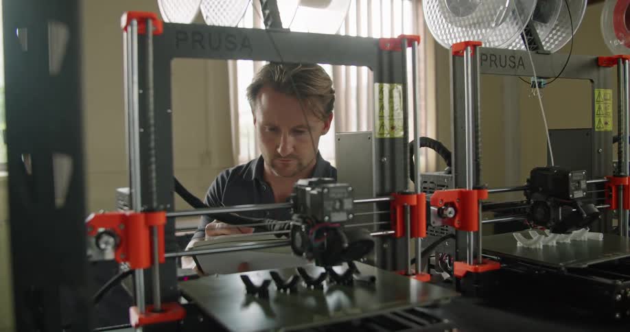 A man working in a shop with a 3d printer