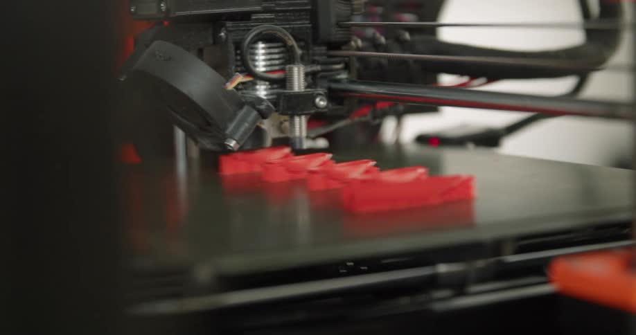 A red zigzag object is printed on a 3d printer