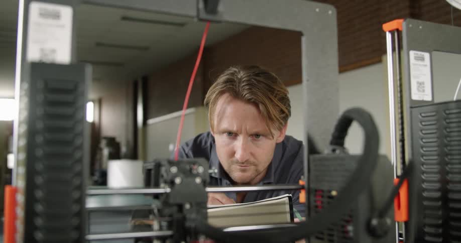 A man that is watching 3d printers working