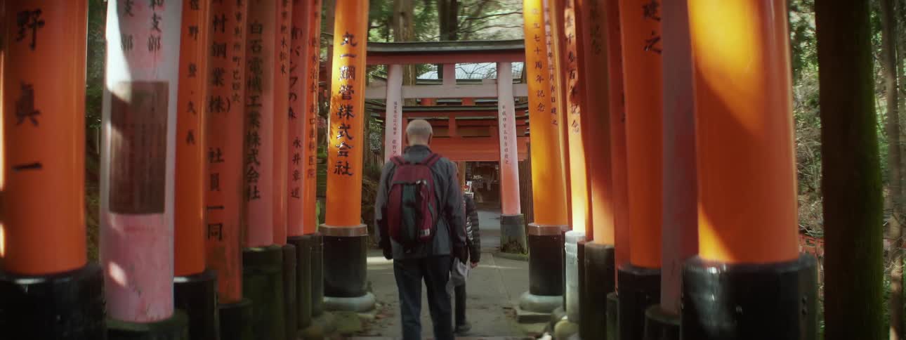 Tourists walk through a row of orange pillars