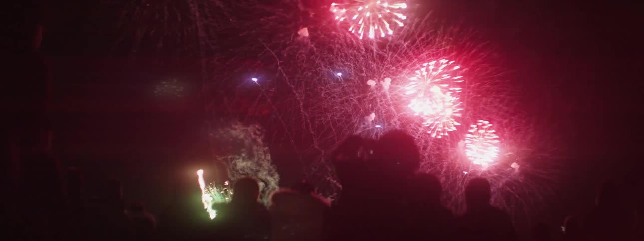 Silhouette of people with exploding fireworks and smoke in the sky