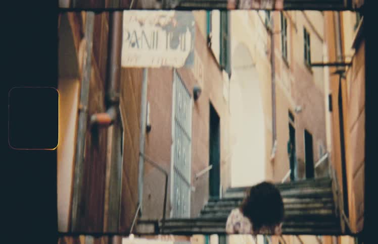 Woman wearing a dress carries suitcase up the stairs of a narrow alleyway