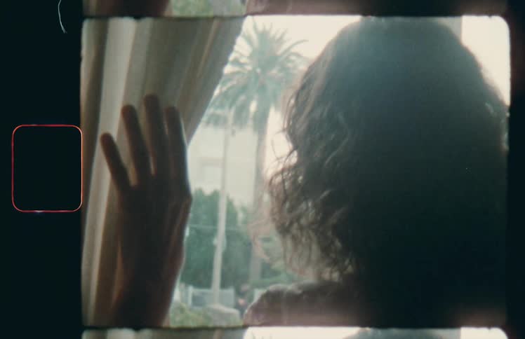 A woman pulls the curtain back to look out her window