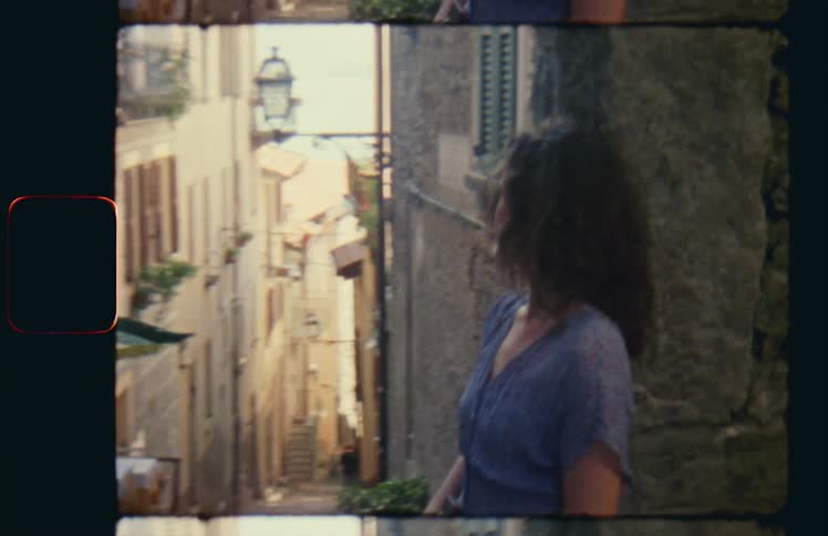 A woman stands in between buildings in a neighborhood