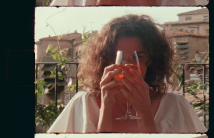 Woman standing outdoors holds a glass of sangria in front of the camera