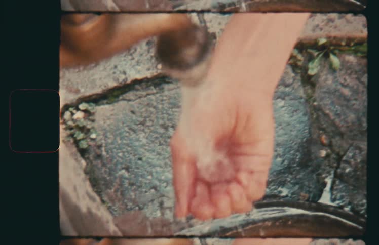 A woman washes her hand at an outdoor faucet
