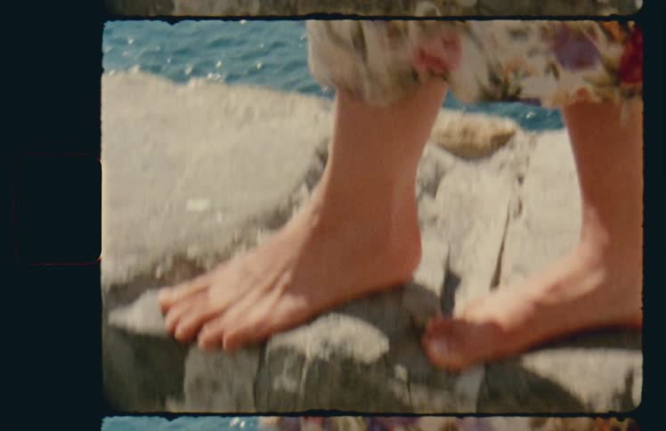 Woman walks on cement wall near ocean