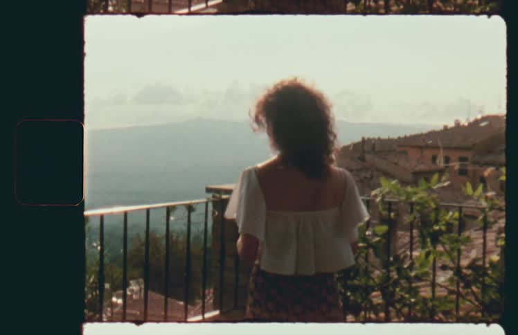 Young woman stands on a balcony in a windy weather