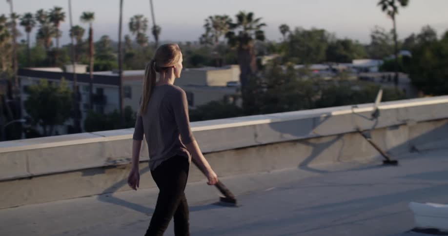 Ponytailed woman walking across a rooftop